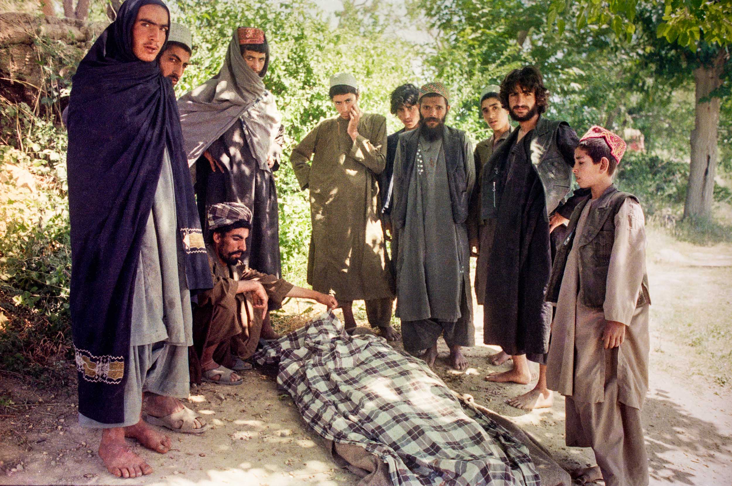 A group of  Mujahideen gather around a dead Mujahideen killed in a bombing run by a Russian plane, Afghanistan 1988
