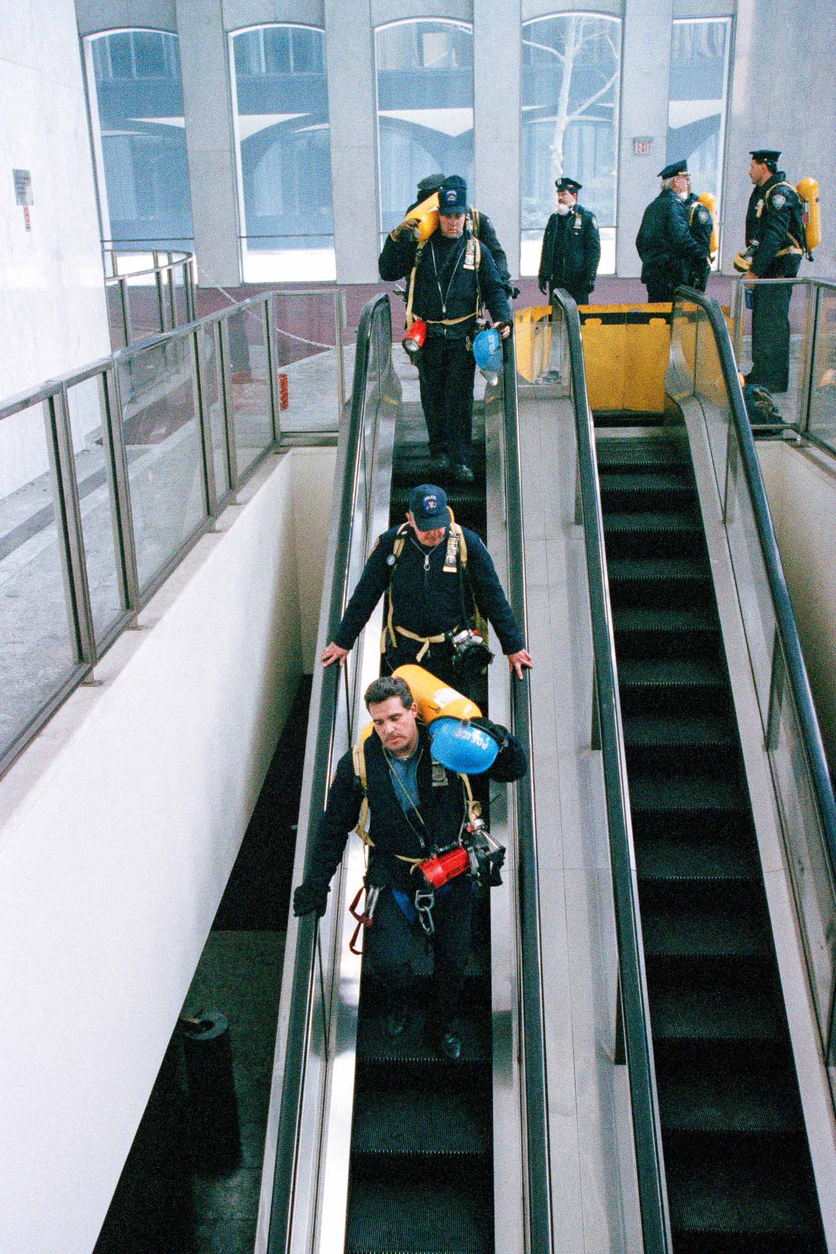 Firemen carrying oxygen tanks descend an escalator to the lower  lobby of the World Trade Center, NY, 1993